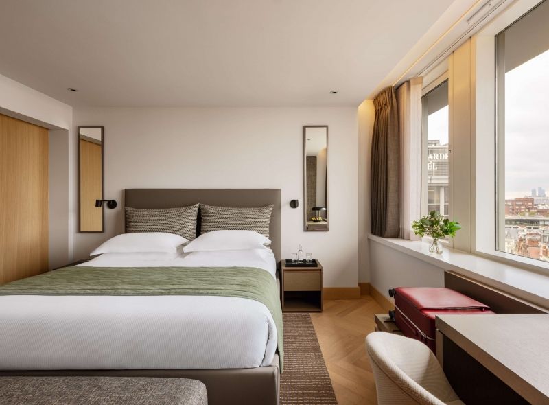 Royal Deluxe Double Room at Royal Garden Hotel with luxurious king bed, bedside table, a comfortable work desk and a panoramic window view.